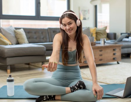 Téléchargez les photos : Jeune femme adulte pratiquant le yoga se sentant heureuse, réussie et confiante, faisant face à un défi et disant apporter ! ou vous accueillir - en image libre de droit