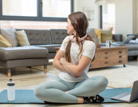 Téléchargez les photos : Jeune femme adulte pratiquant le yoga sur la vue de profil cherchant à copier l'espace devant, penser, imaginer ou rêver - en image libre de droit