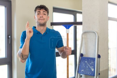 Photo for Young handsome man crossing fingers and hoping for good luck. windows washer concept - Royalty Free Image