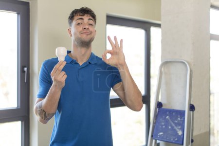 Photo for Young handsome man feeling happy, showing approval with okay gesture. handyman concept - Royalty Free Image