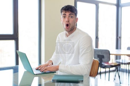 Photo for Young handsome man feeling extremely shocked and surprised. working at home concept - Royalty Free Image