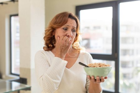 Photo for Middle age pretty woman feeling scared, worried or angry and looking to the side. breakfast bowl concept - Royalty Free Image