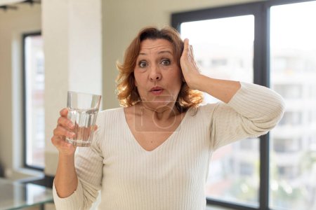 Photo for Middle age pretty woman feeling extremely shocked and surprised. water glass - Royalty Free Image