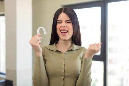 Foto de Mujer joven bonita mirando enojado, molesto y frustrado. concepto de retenedor dental - Imagen libre de derechos
