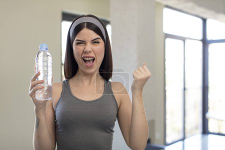 Foto de Mujer joven bonita mirando enojado, molesto y frustrado. concepto de botella de agua - Imagen libre de derechos