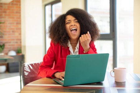 Foto de Mujer negra bastante afro buscando enojado, molesto y frustrado. concepto de mujer de negocios y portátil - Imagen libre de derechos
