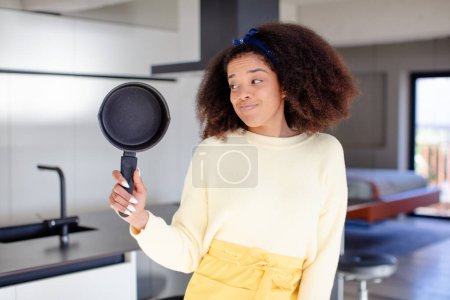Foto de Bonita mujer negra afro sonriendo y mirando con una expresión de confianza feliz. concepto de chef casero - Imagen libre de derechos
