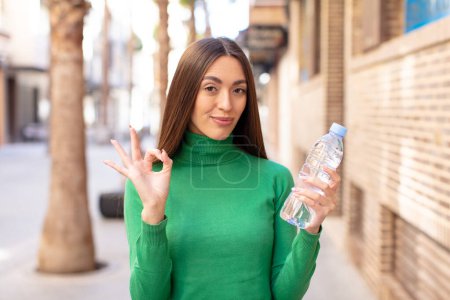 Téléchargez les photos : Se sentir heureux, montrer son approbation avec un geste correct. concept de bouteille d'eau - en image libre de droit