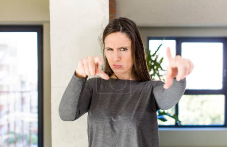Photo for Young adult pretty woman pointing forward at camera with both fingers and angry expression, telling you to do your duty - Royalty Free Image