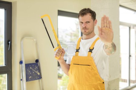 Photo for Looking serious showing open palm making stop gesture. handyman saw concept - Royalty Free Image
