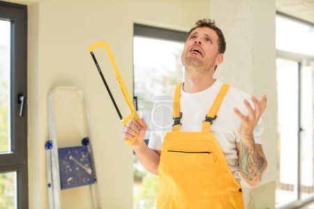 Photo for Screaming with hands up in the air. handyman saw concept - Royalty Free Image