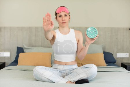 Photo for Looking serious showing open palm making stop gesture. alarm clock concept - Royalty Free Image