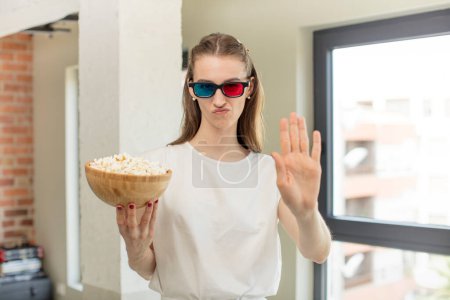Photo for Looking serious showing open palm making stop gesture. popcorns and film concept - Royalty Free Image