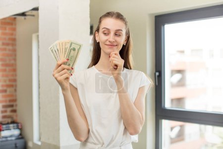 Foto de Sonriendo con una expresión feliz y segura con la mano en la barbilla. concepto de billetes en dólares - Imagen libre de derechos