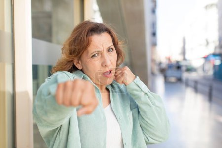 Photo for Middle age woman looking confident, angry, strong and aggressive, with fists ready to fight in boxing position - Royalty Free Image
