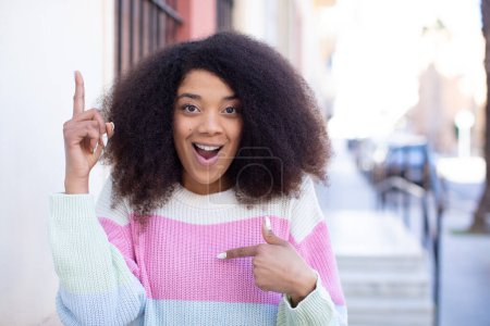 Téléchargez les photos : Afro-américaine jolie femme se sentant fière et surprise, pointant vers soi avec confiance, se sentant comme le succès numéro un - en image libre de droit