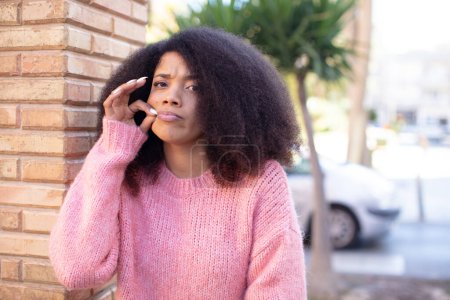 Téléchargez les photos : Afro-américaine jolie femme à l'air grave et mécontente avec les deux doigts croisés en avant dans le rejet, demandant le silence - en image libre de droit