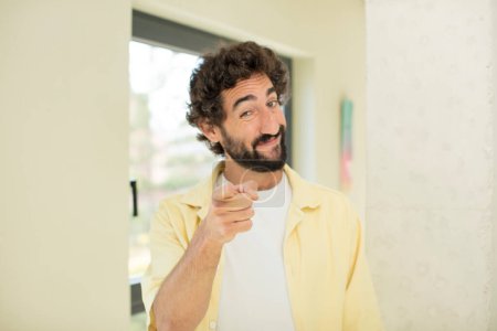 Photo for Young crazy bearded man pointing at camera with a satisfied, confident, friendly smile, choosing you - Royalty Free Image