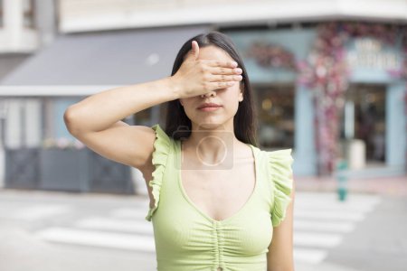 Photo for Pretty hispanic woman covering eyes with one hand feeling scared or anxious, wondering or blindly waiting for a surprise - Royalty Free Image