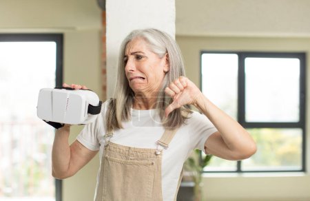 Photo for Pretty senior woman feeling cross,showing thumbs down. with vr goggles - Royalty Free Image