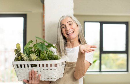 Photo for Pretty senior woman smiling happily and offering or showing a concept. gardener concept - Royalty Free Image