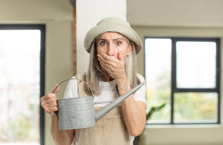 Photo for Pretty senior woman covering mouth with a hand and shocked or surprised expression. gardener concept - Royalty Free Image
