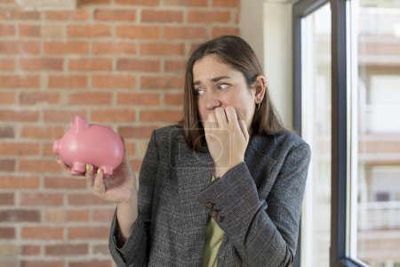 Photo for Young pretty woman feeling scared, worried or angry and looking to the side. piggy bank concept - Royalty Free Image