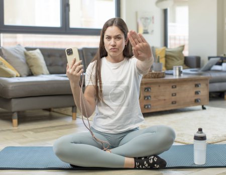 Foto de Joven bonita mujer mirando serio mostrando abierta palma haciendo gesto de parada. concepto de yoga - Imagen libre de derechos