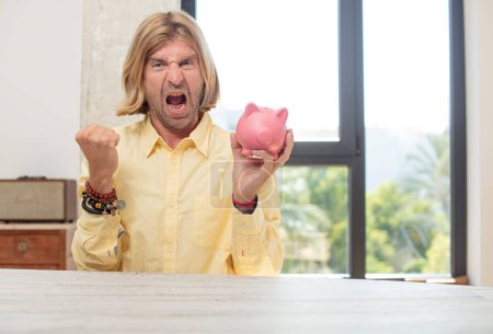 Photo for Young adult caucasian man looking angry, annoyed and frustrated. piggy bank concept - Royalty Free Image