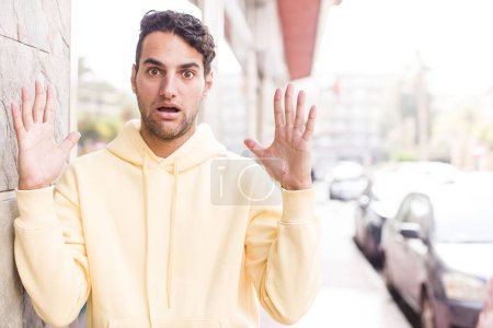 Téléchargez les photos : Jeune homme hispanique tenant un objet avec les deux mains, montrant, offrant ou annonçant un objet - en image libre de droit