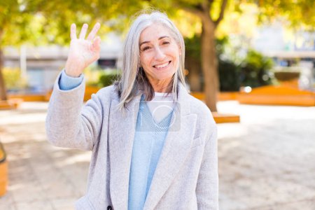 Foto de Senior jubilado bastante blanco cabello mujer sintiéndose feliz, relajado y satisfecho, mostrando aprobación con gesto bien, sonriendo - Imagen libre de derechos
