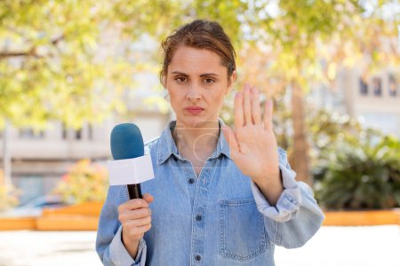 Photo for Young pretty woman looking serious showing open palm making stop gesture. presenter and microphone concept - Royalty Free Image