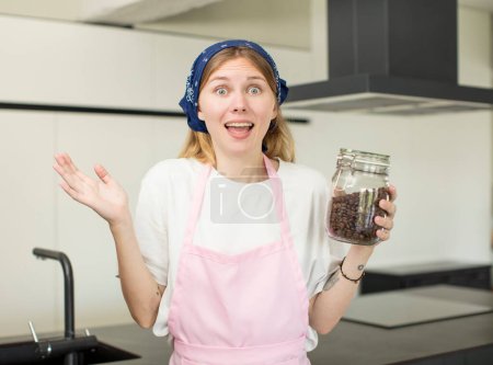 Foto de Joven bonita mujer sintiéndose feliz y asombrada por algo increíble. chef casero con granos de café - Imagen libre de derechos