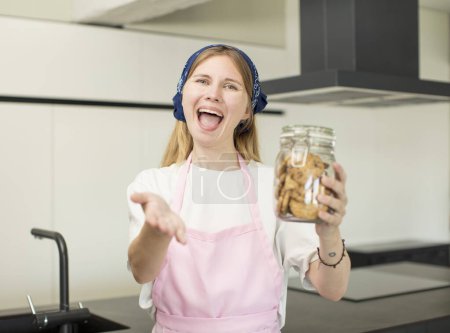 Photo for Young pretty woman smiling happily and offering or showing a concept. home made cookies - Royalty Free Image
