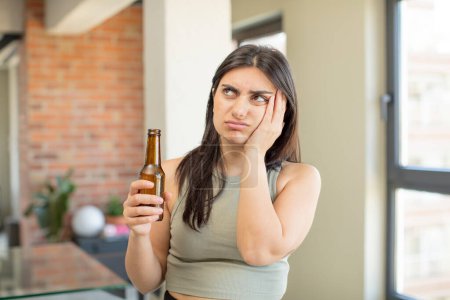 Foto de Mujer joven que se siente aburrida, frustrada y somnolienta después de un cansancio. botella de cerveza - Imagen libre de derechos