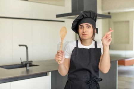 Foto de Mujer joven cruzando los dedos y esperando buena suerte. concepto de chef - Imagen libre de derechos