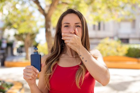 Photo for Pretty woman covering mouth with a hand and shocked or surprised expression. vaper concept - Royalty Free Image
