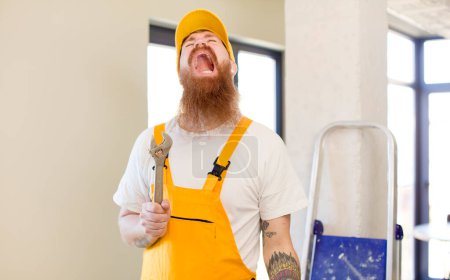 Téléchargez les photos : Homme aux cheveux roux criant avec les mains en l'air réparer la maison. concept bricoleur - en image libre de droit