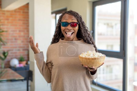 Téléchargez les photos : Noir afro femme se sentir heureux et étonné de quelque chose d'incroyable avec popcorns - en image libre de droit