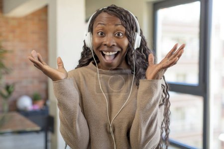 Foto de Negro afro mujer sintiéndose feliz y asombrado por algo increíble. escuchar música concepto - Imagen libre de derechos