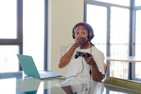 Photo for Black afro woman covering mouth with a hand and shocked or surprised expression. gamer concept - Royalty Free Image