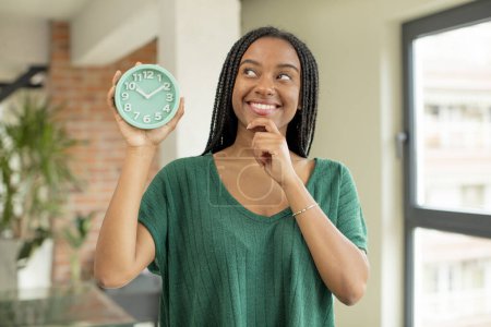 Foto de Mujer afro negro sonriendo con una expresión feliz y segura con la mano en la barbilla. concepto de despertador - Imagen libre de derechos