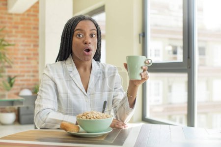 Téléchargez les photos : Afro noir femme se sentant extrêmement choqué et surpris. concept de petit déjeuner - en image libre de droit