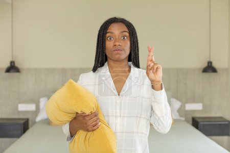Foto de Mujer afro negro cruzando los dedos y esperando buena suerte. concepto de descanso y ropa de dormir - Imagen libre de derechos