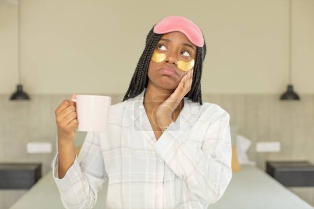 Téléchargez les photos : Noir afro femme se sentir ennuyé, frustré et somnolent après un fatigant. concept de repos et vêtements de nuit - en image libre de droit
