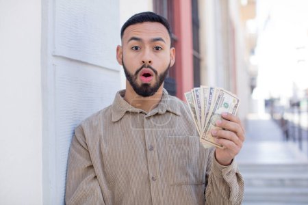 Photo for Young  adult man feeling extremely shocked and surprised. dollar banknotes concept - Royalty Free Image