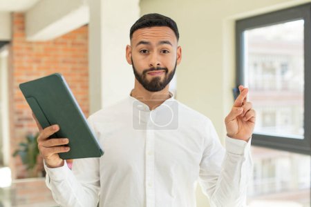 Foto de Hombre joven adulto cruzando los dedos y esperando buena suerte. concepto de pantalla táctil pad - Imagen libre de derechos
