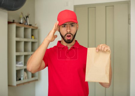 Photo for Young  adult man looking happy, astonished and surprised. deliveryman concept - Royalty Free Image