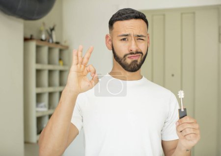 Photo for Young  adult man feeling happy, showing approval with okay gesture. home key concept - Royalty Free Image