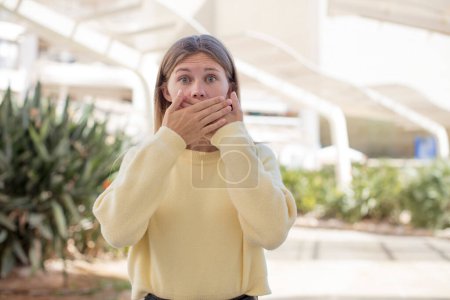 Photo for Pretty young woman covering mouth with hands with a shocked, surprised expression, keeping a secret or saying oops - Royalty Free Image